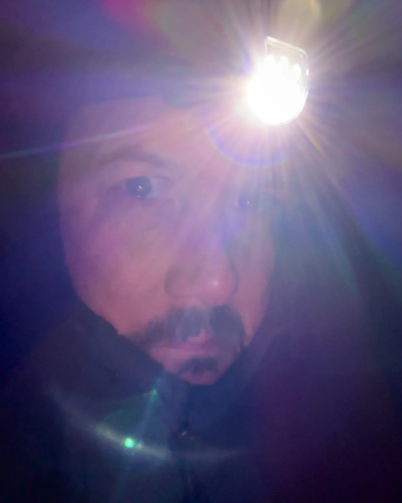 Selfie wearing a head torch in the dark.